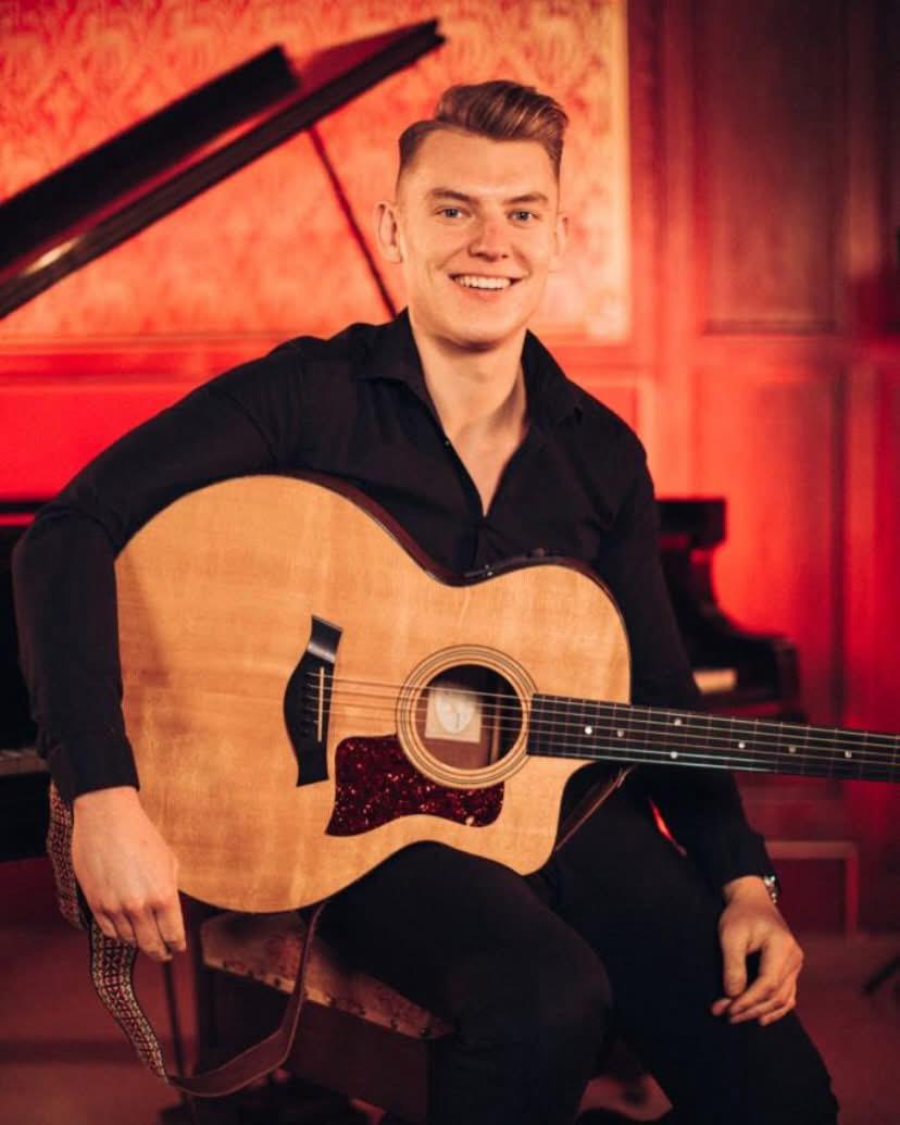 Sam performing with acoustic guitar